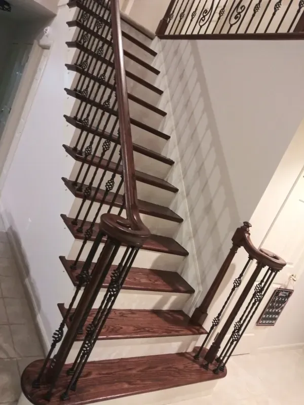 A wooden staircase with a wrought iron railing in a hallway