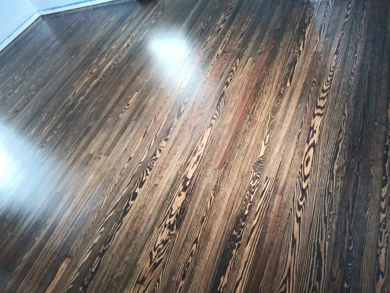 A dark wooden floor with a few spots of light on it