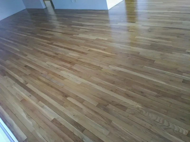 A wooden floor in a living room with a sliding glass door.