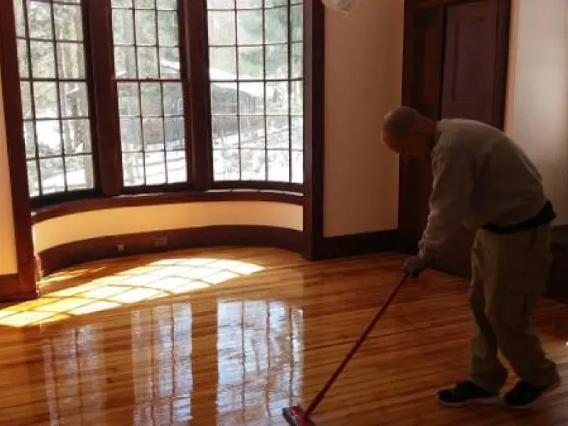 A man cleaning a wooden floor with a mop