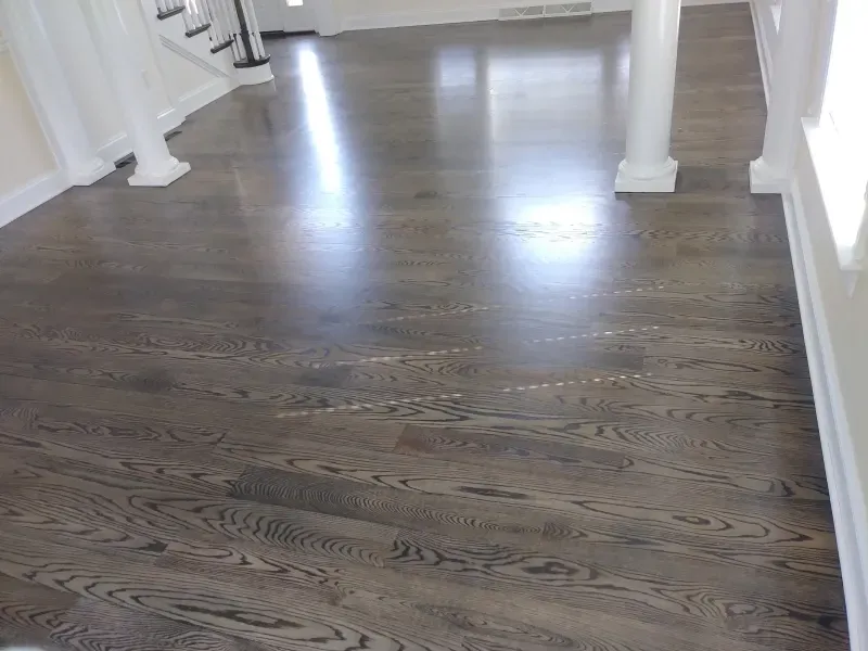 A wooden floor in a room with stairs and columns.