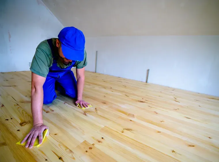 A man is cleaning a wooden floor with a cloth.